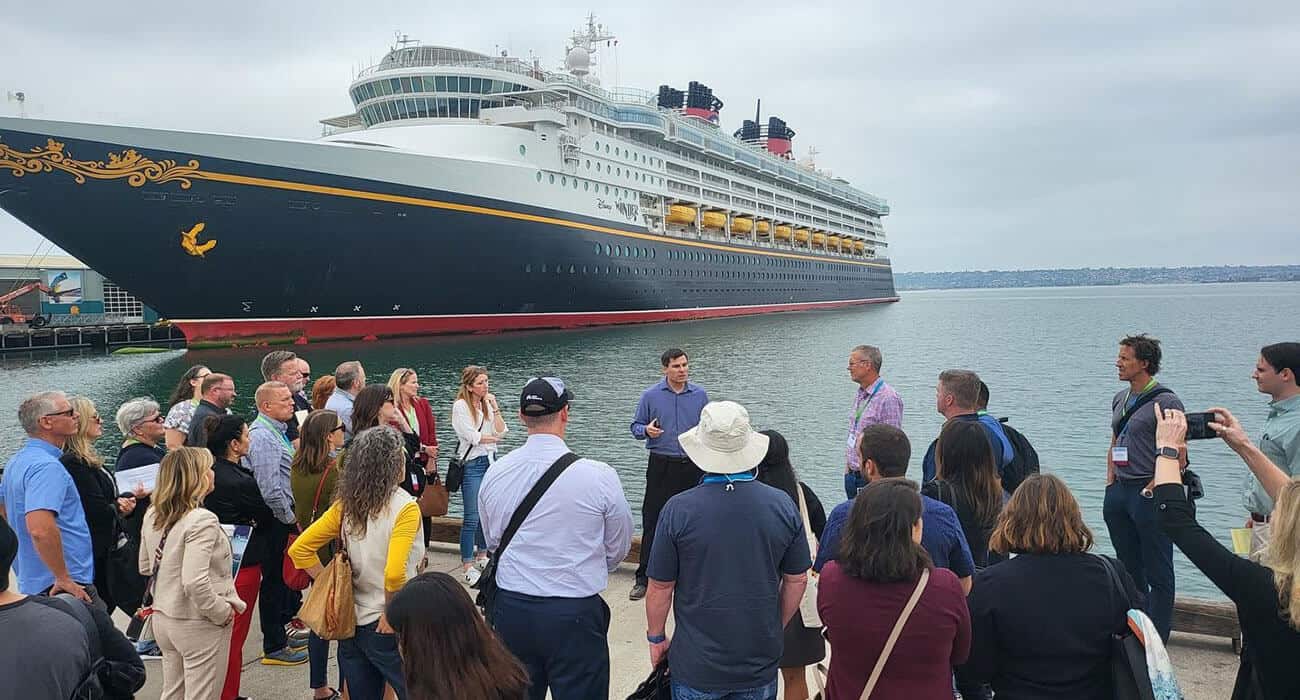 Group of people standing on dock in front of large cruise ship