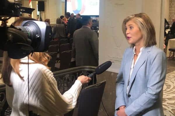 News camera crew interviewing woman at a convention